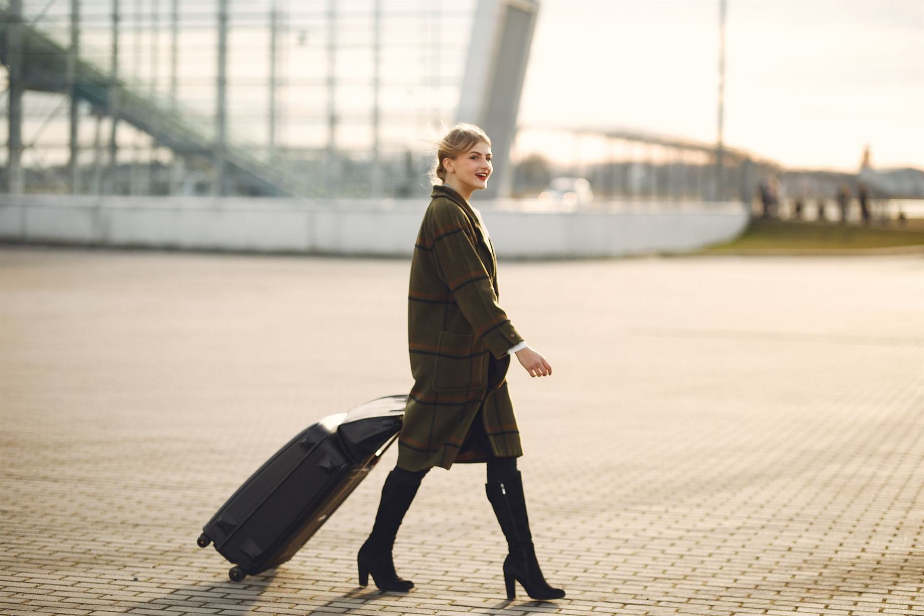 A woman walking with her suitcase near an airport