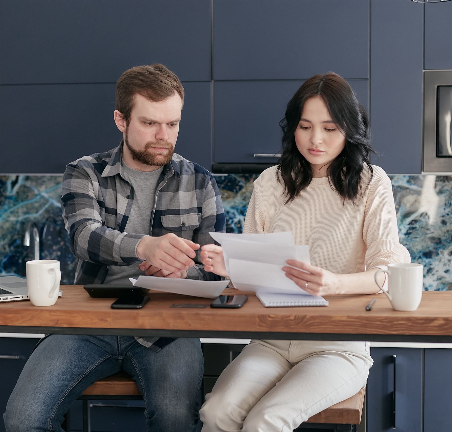 A couple sitting at a table going through their bills and paperwork together