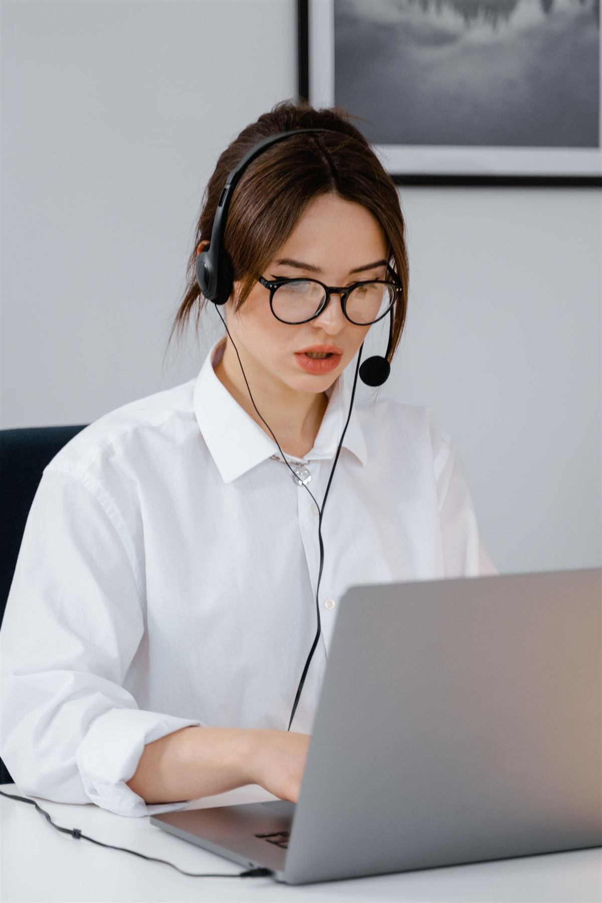 A smiling support agent wearing a headset while working at her laptop