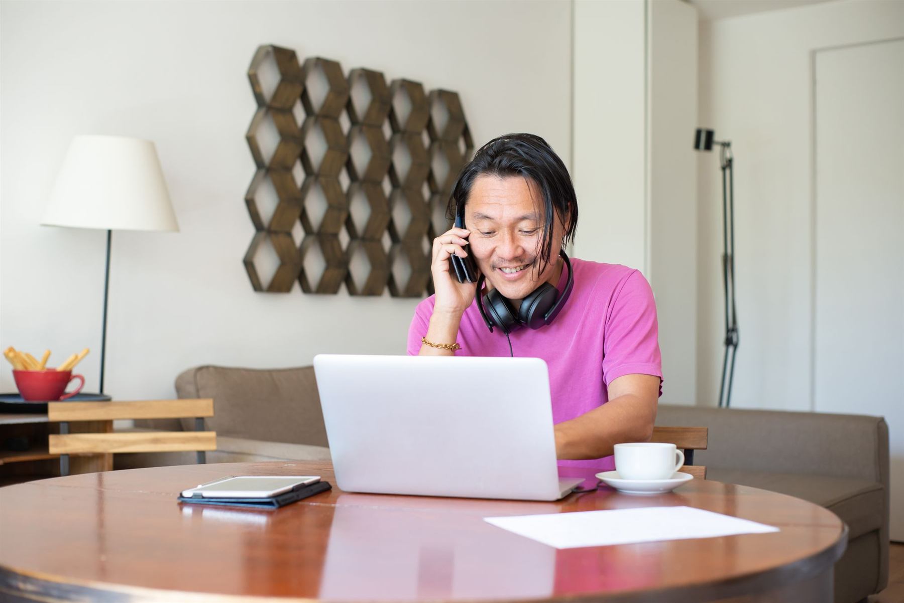 A man at home talking on the phone while working at his laptop